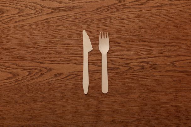 top view of wooden fork and knife on brown background - Fotoğraf, Görsel