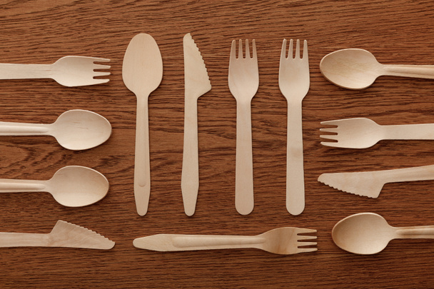 vista superior de cucharas de madera tenedores y cuchillos sobre fondo marrón
 - Foto, Imagen