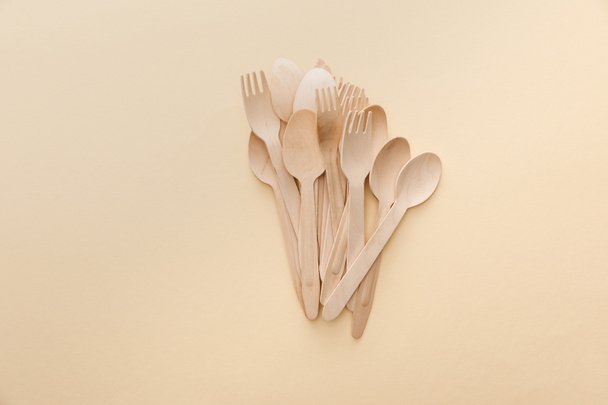 vista dall'alto di cucchiai e forchette in legno naturale su sfondo beige
 - Foto, immagini
