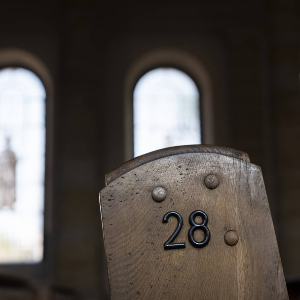 число 28 на стороне старой деревянной церковной скамьи с римскими окнами
  - Фото, изображение