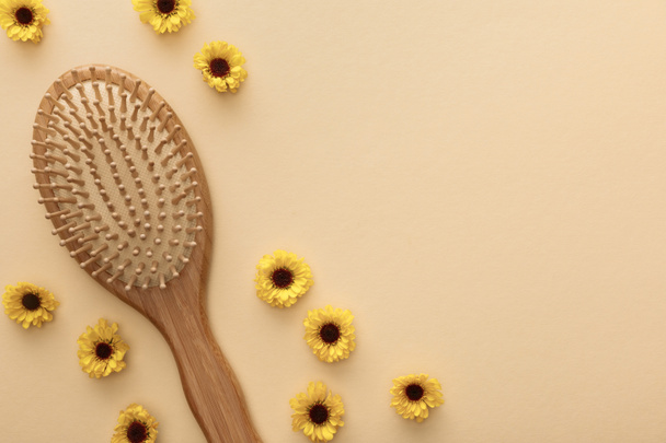 vista superior del cepillo de pelo sobre fondo beige con flores y espacio de copia
 - Foto, Imagen