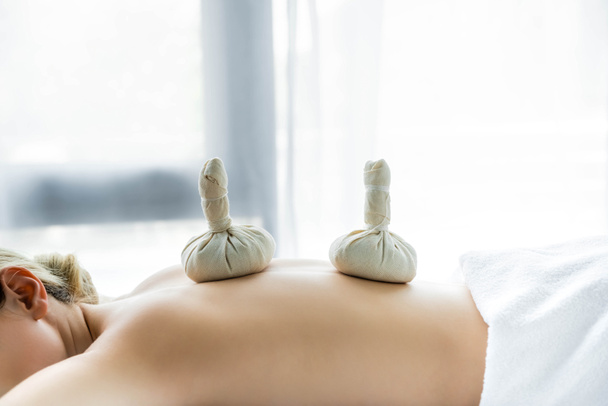 woman lying on massage mat with herbal balls on back  - Photo, Image