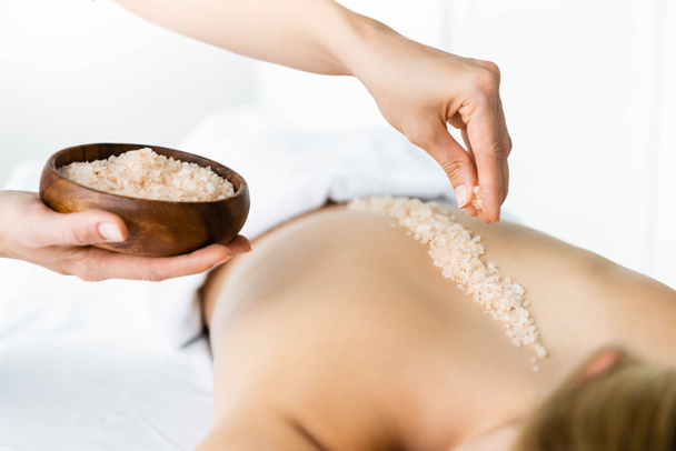 cropped view of masseur applying sea salt on back of woman  - Photo, Image