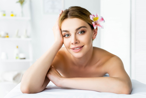 attraente e sorridente donna con fiore sdraiato sul tappeto da massaggio
 - Foto, immagini