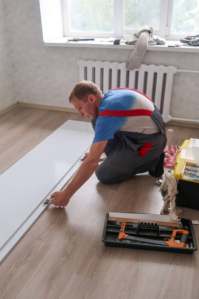 ペトロパブロフスク、カザフスタン - 2019年8月22日:男がアパートで家具を収集します。修理作業 - 写真・画像
