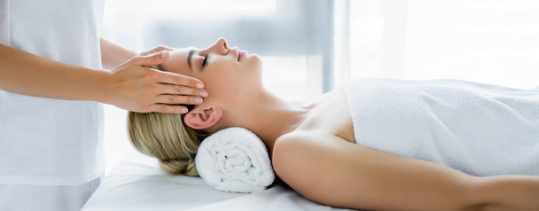 panoramische foto van masseur doet gezicht massage naar aantrekkelijke vrouw  - Foto, afbeelding