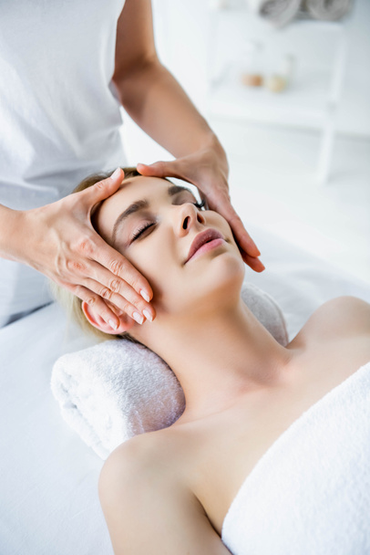recortado vista de masajista haciendo masaje facial a atractiva mujer
  - Foto, Imagen