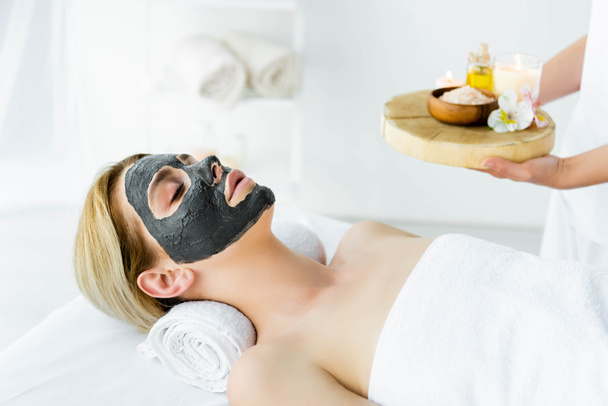 atractiva mujer con máscara de arcilla en la cara acostado en el spa
  - Foto, imagen