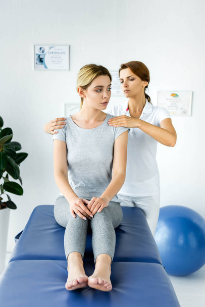 quiropráctico tocando hombros de paciente atractivo en camiseta gris
  - Foto, Imagen