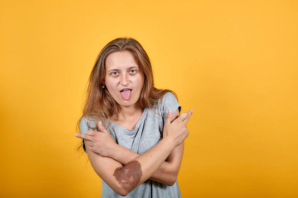 brunette meisje in grijs t-shirt over geïsoleerde oranje achtergrond toont emoties - Foto, afbeelding