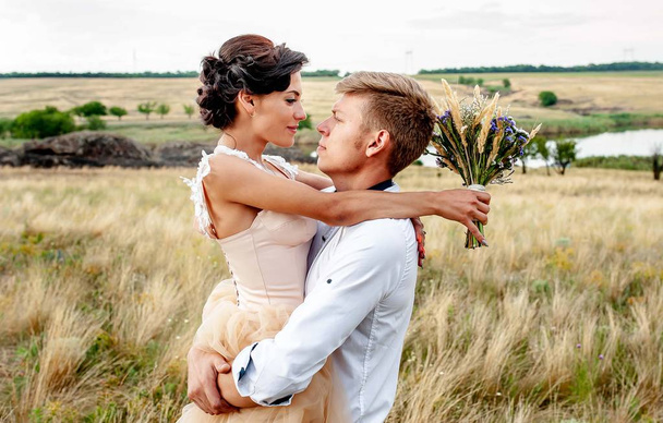 couple of bride and groom hugging together in field - 写真・画像