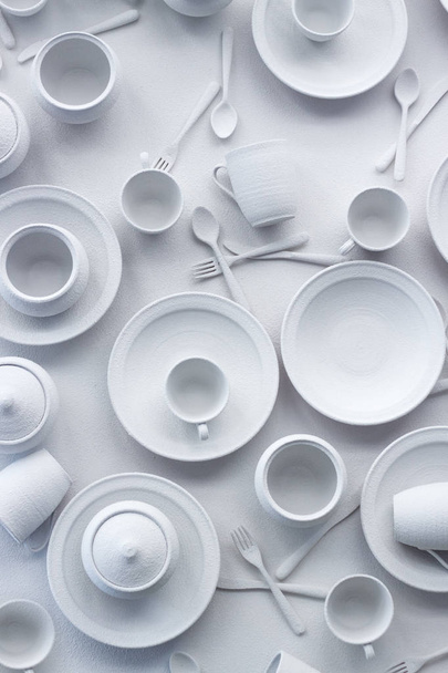 Muitos pratos e aparelhos são pintados de branco em uma superfície branca, o conceito de consumo excessivo, foco seletivo
 - Foto, Imagem