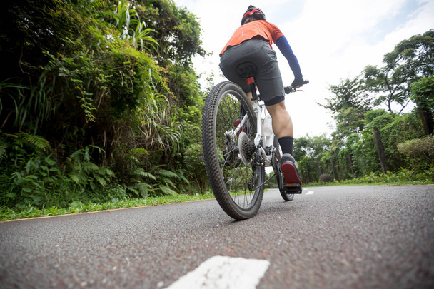 Жінка-велосипедистка їде на гірському велосипеді на тропічній тропічній лісовій стежці
 - Фото, зображення