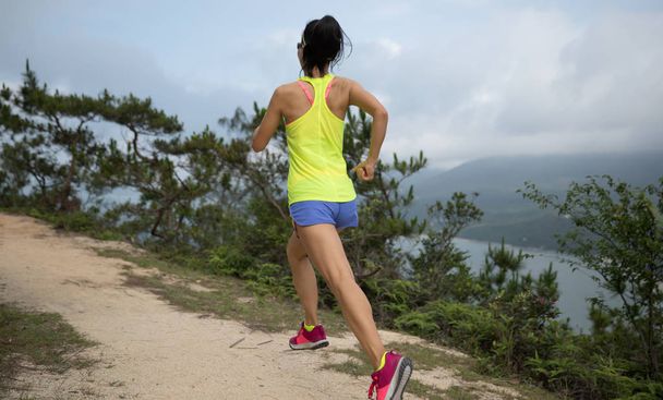 Jovem esportiva em trilha de roupas esportivas correndo no caminho da montanha da floresta. Fitness girl jogging em Hong Kong
 - Foto, Imagem