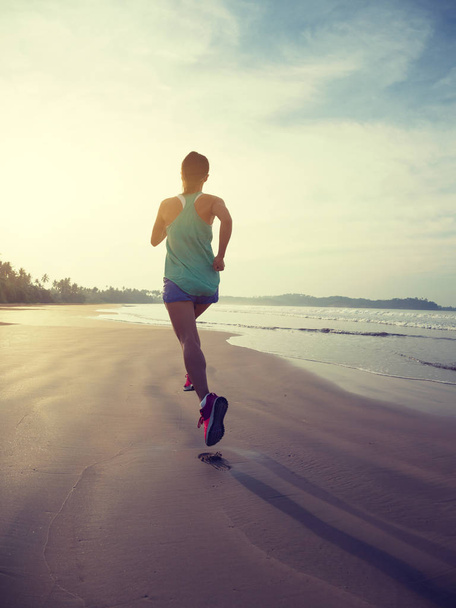 Спортивная спортсменка бегает по пляжу на восходе солнца
 - Фото, изображение