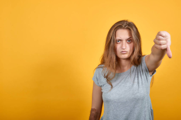 brunette tyttö harmaa t-paita yli eristetty oranssi tausta osoittaa tunteita
 - Valokuva, kuva