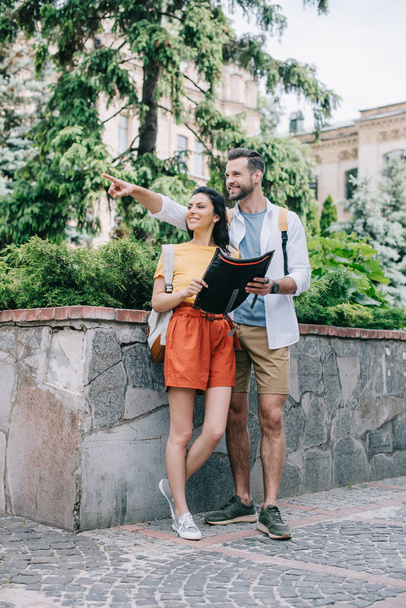 mutlu adam harita tutarken ve kadın ile ayakta parmak ile işaret  - Fotoğraf, Görsel