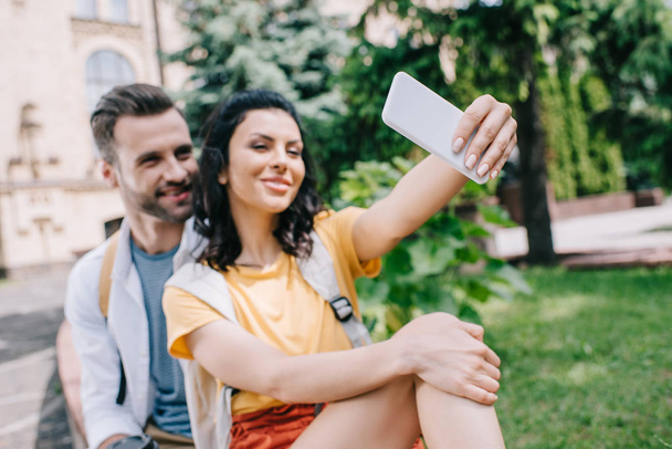 selective focus of happy woman talking selfie with handsome man near building  - Photo, Image