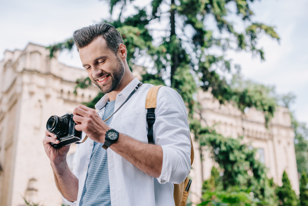 low angle view of cheerful bearded man holding digital camera  - Fotoğraf, Görsel