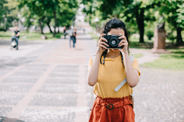 young woman covering face while taking photo on digital camera  - Foto, Imagen