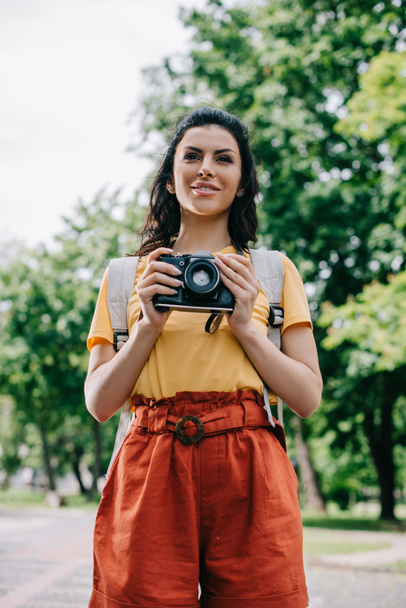 happy young woman holding digital camera outside  - Фото, зображення