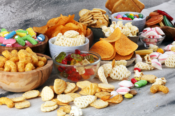 Salty snacks. Pretzels, chips, crackers and candy sweets on tabl - Photo, Image