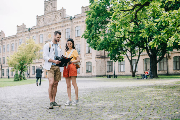 KYIV, UKRAINE - MAY 28, 2019: handsome man and attractive girl standing near building with map  - Foto, Imagem