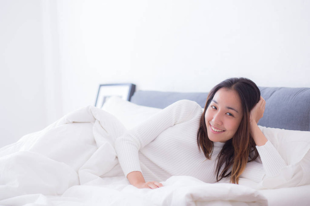 Een blij slapen op de kant van een jonge vrouw lachend zachtjes in bed - Foto, afbeelding