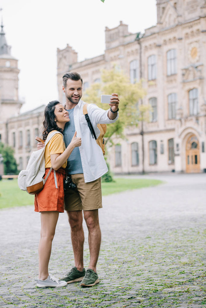 happy bearded man and attractive young woman taking selfie near building  - Foto, imagen