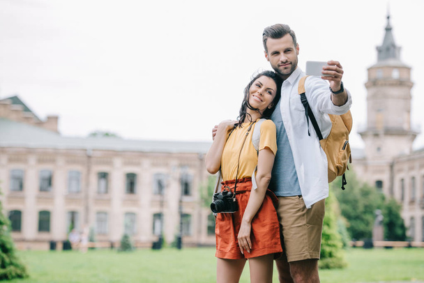 happy bearded man and attractive woman taking selfie near building  - Foto, Imagem