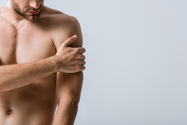 vista parcial del hombre musculoso sin camisa con dolor en el brazo aislado en gris
 - Foto, imagen