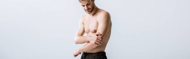 panoramic shot of shirtless man with pain in elbow isolated on grey - Photo, Image