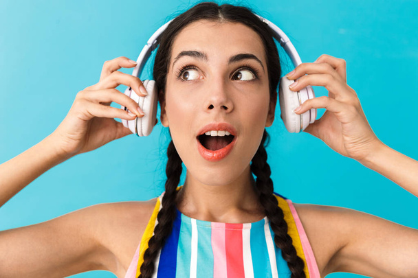 Image closeup of brunette pleased woman looking aside with open mouth while using headphones - Foto, imagen