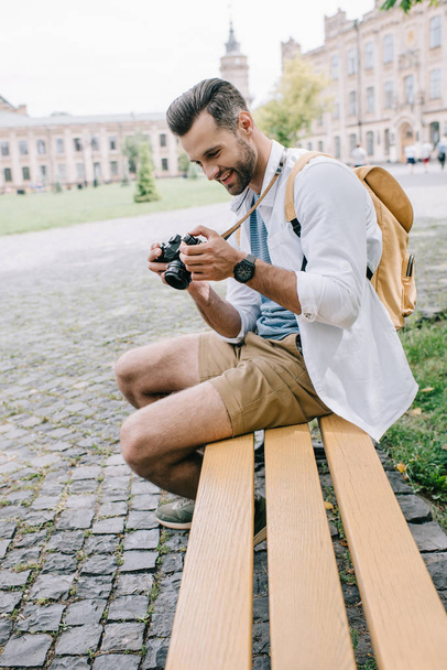selective focus of happy man looking at digital camera while sitting on bench  - Фото, зображення