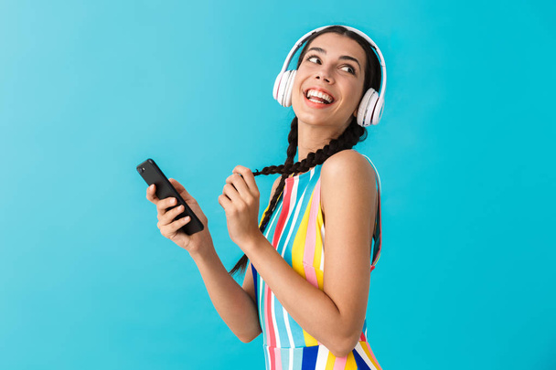 Image of nice beautiful woman with pigtails looking aside while using headphones and cellphone - Valokuva, kuva