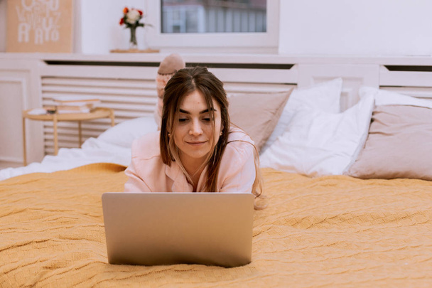 Szczęśliwa dziewczyna przeglądanie Internetu w laptopie w sypialni w domu - Zdjęcie, obraz