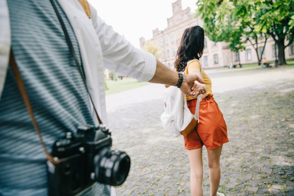 Ausgeschnittene Ansicht eines Mannes, der Händchen hält mit einem Mädchen, das in der Nähe der Universität geht  - Foto, Bild