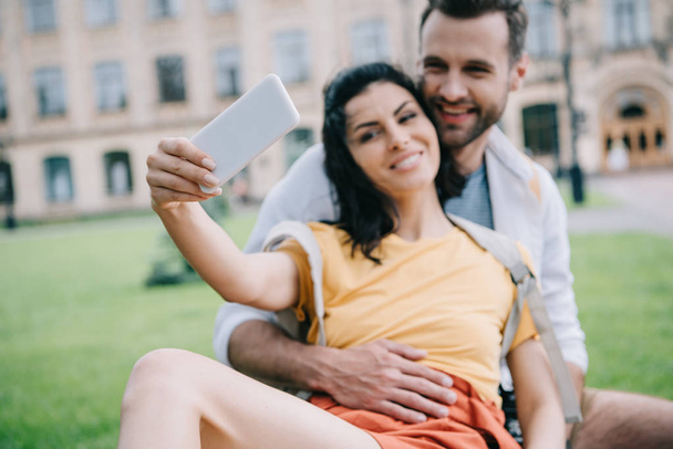 selective focus of happy couple taking selfie near building  - Fotografie, Obrázek