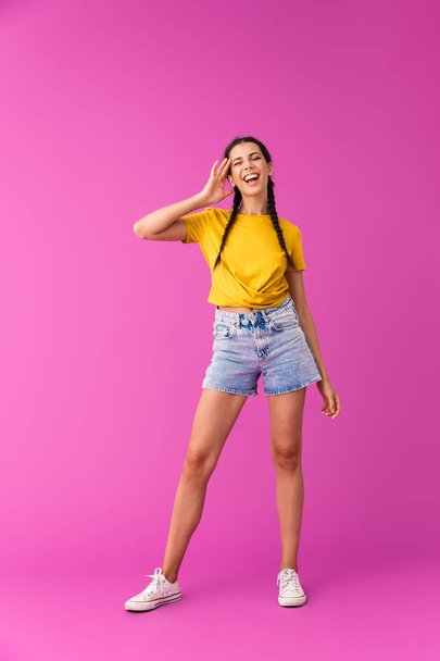 Full length photo of young caucasian woman wearing denim shorts winking and touching her temple - Fotó, kép