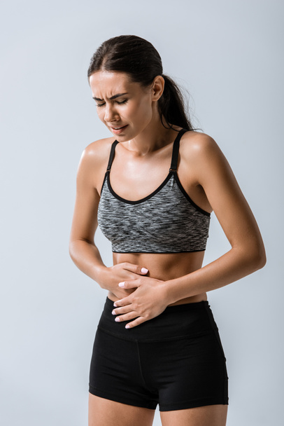 attractive sportswoman with stomach pain isolated on grey - Fotografie, Obrázek