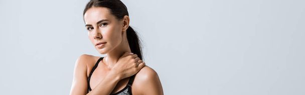 panoramic shot of attractive sportswoman with neck pain isolated on grey - Foto, afbeelding
