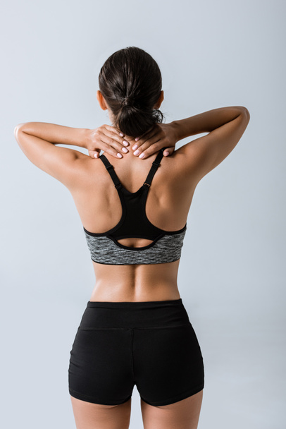 back view of sportswoman with neck pain isolated on grey - Zdjęcie, obraz