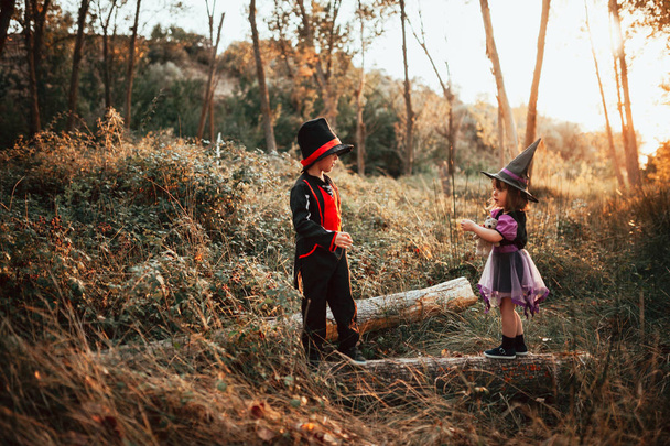 Двоє дітей, замаскованих на Хелловін у лісі
 - Фото, зображення
