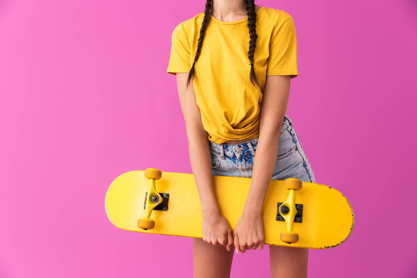 Cropped image of skinny caucasian woman standing and holding skateboard - Photo, image