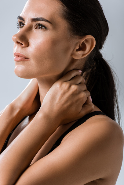 attractive sportswoman with neck pain isolated on grey - 写真・画像