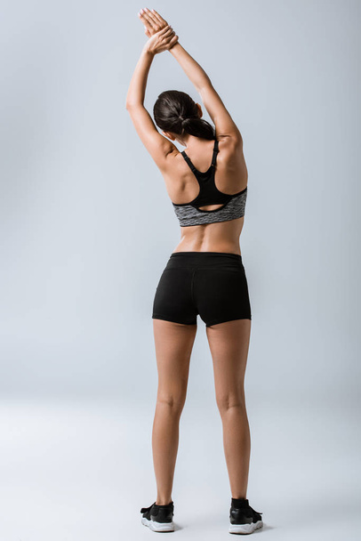 back view of sexy sportswoman warming up on grey - Φωτογραφία, εικόνα