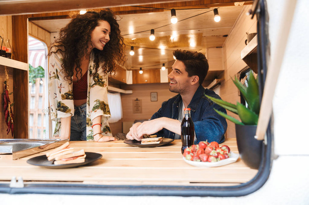 Romantic cheery couple man and woman in trailer mobile home have a dinner. - Foto, afbeelding