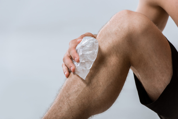 partial view of sportsman using ice for knee isolated on grey - Foto, Imagen
