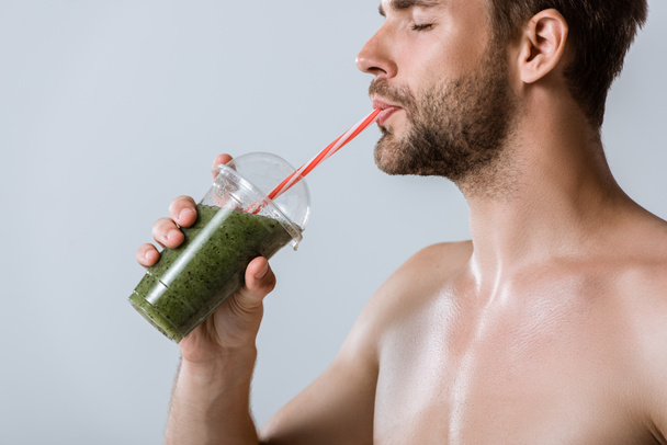 shirtless bearded sportsman drinking smoothie isolated on grey - Foto, imagen