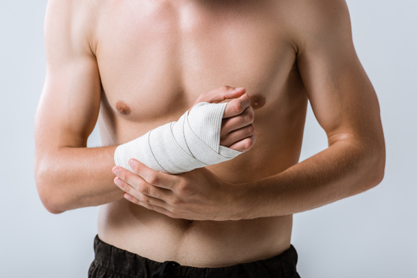 Ausgeschnittene Ansicht eines hemdlosen Sportlers mit elastischem Verband am Handgelenk isoliert auf grau - Foto, Bild